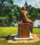 A seated female figure strikes a casual pose, body half turned in this imposing sculpture by American artist, Jason Kimes. Image 7