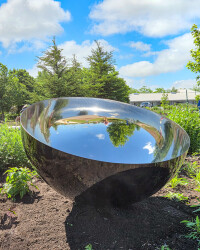 This contemporary outdoor sculpture is a metal vessel in a mirrored and black finish.