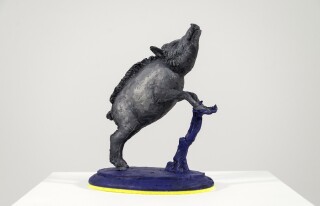 Cast in resin, a figurine of a boar posed on an indigo base points to a theme of human and animal interaction that includes taxidermy.