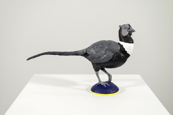 Cast in resin, a figurine of a pheasant posed on an indigo base points to a theme of human and animal interaction.