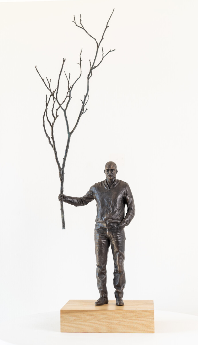 This indoor table top figurative sculpture of a male is cast in bronze.