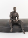 This indoor table top bronze sculpture features a man sitting on an overturned canoe. Image 7