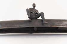 This indoor table top bronze sculpture features a man sitting on an overturned canoe. Image 10