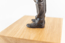 This indoor table top figurative sculpture of a male is cast in bronze. Image 6