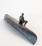 This indoor table top bronze sculpture features a man sitting on an overturned canoe. Image 4