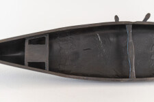 This indoor table top bronze sculpture features a man sitting on an overturned canoe. Image 11
