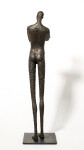 He stands tall—a slender naked figure, arms crossed, head slightly tilted. Image 5