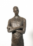 He stands tall—a slender naked figure, arms crossed, head slightly tilted. Image 2