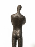 He stands tall—a slender naked figure, arms crossed, head slightly tilted. Image 8