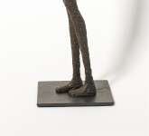 He stands tall—a slender naked figure, arms crossed, head slightly tilted. Image 7