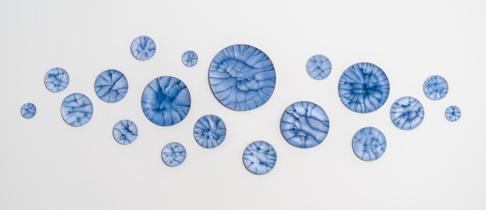 This contemporary horizontal wall composition by Paula Murray is composed of blue porcelain discs.