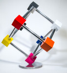 In this dynamic sculpture by Phillipe Pallafray, an open 3D stainless steel cube; each point connected by a brightly coloured solid cube in … Image 5