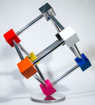 In this dynamic sculpture by Phillipe Pallafray, an open 3D stainless steel cube; each point connected by a brightly coloured solid cube in … Image 6