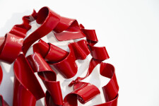 In a gorgeous candy coloured red, ribbons of steel swirl together curling and overlapping to form a circle. Image 8