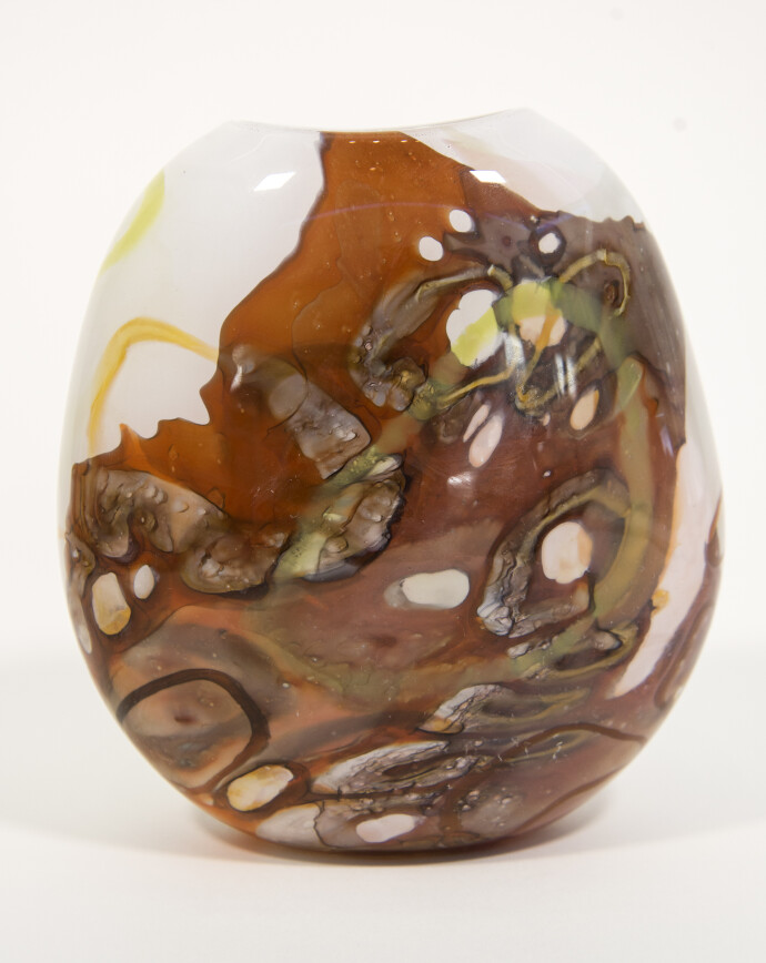 Earthy colours of gold, lime green and chestnut brown swirl in patterns on this lovely glass vessel by Canadian artist Susan Rankin.