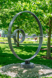 This contemporary outdoor kinetic sculpture is forged from steel into a circle.